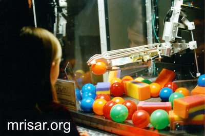 Robotic Exhibits; The early version (2001) of MRISAR's Top mounted 5 Finger Robotic Arm Exhibit. Testing it is MRISAR Team member Autumn Siegel. She is one of the youngest members of the MRISAR team and began her apprenticeship as a preschooler. MRISAR has designed and fabricated the earth’s largest selection of world-class, public use, interactive robotic exhibits.